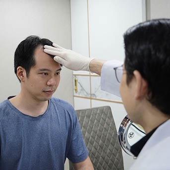 แพทย์ตรวจแนวไรผมก่อนปลูกผม ระหว่างการปรึกษาปลูกผมที่ Facebody Clinic